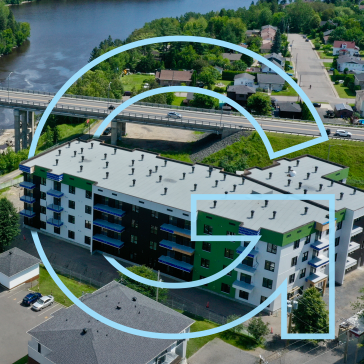 Vue aérienne d’un immeuble résidentiel moderne près d’une rivière et d’un pont, avec un grand élément graphique bleu en forme de lettre G superposé à l’image.